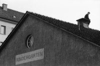 Image of sheet 19900110 photo 13: Portrait vor Ofen im Erismannhof. Städtische Siedlung Zürich 
Iris Zoe und Ruedi Teklenburg. Carla Lia Monti 'Räuberinnen' Ofen Erismannhof 2. Kindergarten. Kinder spielen mit Gewehren. Achmed von Warthburg. Fahrrad in der Stube. X liegt auf Sofa. Carla Lia Monti beim Haareschneiden. Sadam Hussein auf Poster. Zürich 1990
