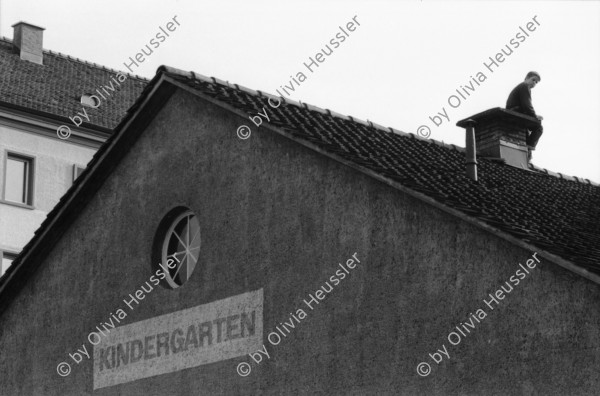 Image of sheet 19900110 photo 13: Portrait vor Ofen im Erismannhof. Städtische Siedlung Zürich 
Iris Zoe und Ruedi Teklenburg. Carla Lia Monti 'Räuberinnen' Ofen Erismannhof 2. Kindergarten. Kinder spielen mit Gewehren. Achmed von Warthburg. Fahrrad in der Stube. X liegt auf Sofa. Carla Lia Monti beim Haareschneiden. Sadam Hussein auf Poster. Zürich 1990