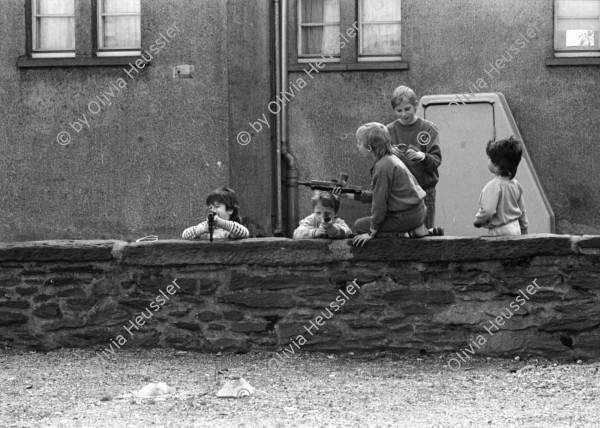 Image of sheet 19900110 photo 15: Portrait vor Ofen im Erismannhof. Städtische Siedlung Zürich 
Iris Zoe und Ruedi Teklenburg. Carla Lia Monti 'Räuberinnen' Ofen Erismannhof 2. Kindergarten. Kinder spielen mit Gewehren. Achmed von Warthburg. Fahrrad in der Stube. X liegt auf Sofa. Carla Lia Monti beim Haareschneiden. Sadam Hussein auf Poster. Zürich 1990