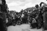 Image of sheet 19900310 photo 22: UN-Helikopter landet unter Aufsicht eines UN Soldaten auf kleinem Hügel in Yamales. Alte ausgediente unbrauchbare Waffen liegen zum symbolischen Zerstörungsakt der UN Truppen auf einer Plane bereit. Junge posiert dazwischen. Portrait Nr. 8 Beretta und Nr. 7 Uzi Italienische und israelische Klein maschinen gewehre. Staub. 12 General Quesada. 13 und 14 Cmdte. Siro Somozist. UN-Soldaten brennen die Waffen nieder. Kriegs Zerstörung mit Flammenwerfer. UN Soldaten sind mit Deutschen Heckler und Koch bewaffnet. Honduras Yamales 1990 rifle weapon arms