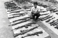 Image of sheet 19900310 photo 5: Ein Junge posiert inmitten Kriegswaffen die die Contra-Rebellen von den Sandinisten erbeuteten, Yamales Honduras 1990.
Kind Waffen rifle boy child weapon ONU UNO

AK-47 ist die Abkürzung für Awtomat Kalaschnikowa, obrasza 47 (kyrillisch Автомат Калашникова образца 47), ein sowjetisch-russisches Sturmgewehr. Es ist die am meisten produzierte Handfeuerwaffe weltweit. Schätzungen gehen von 80 bis 100 Millionen produzierten Exemplaren aus.