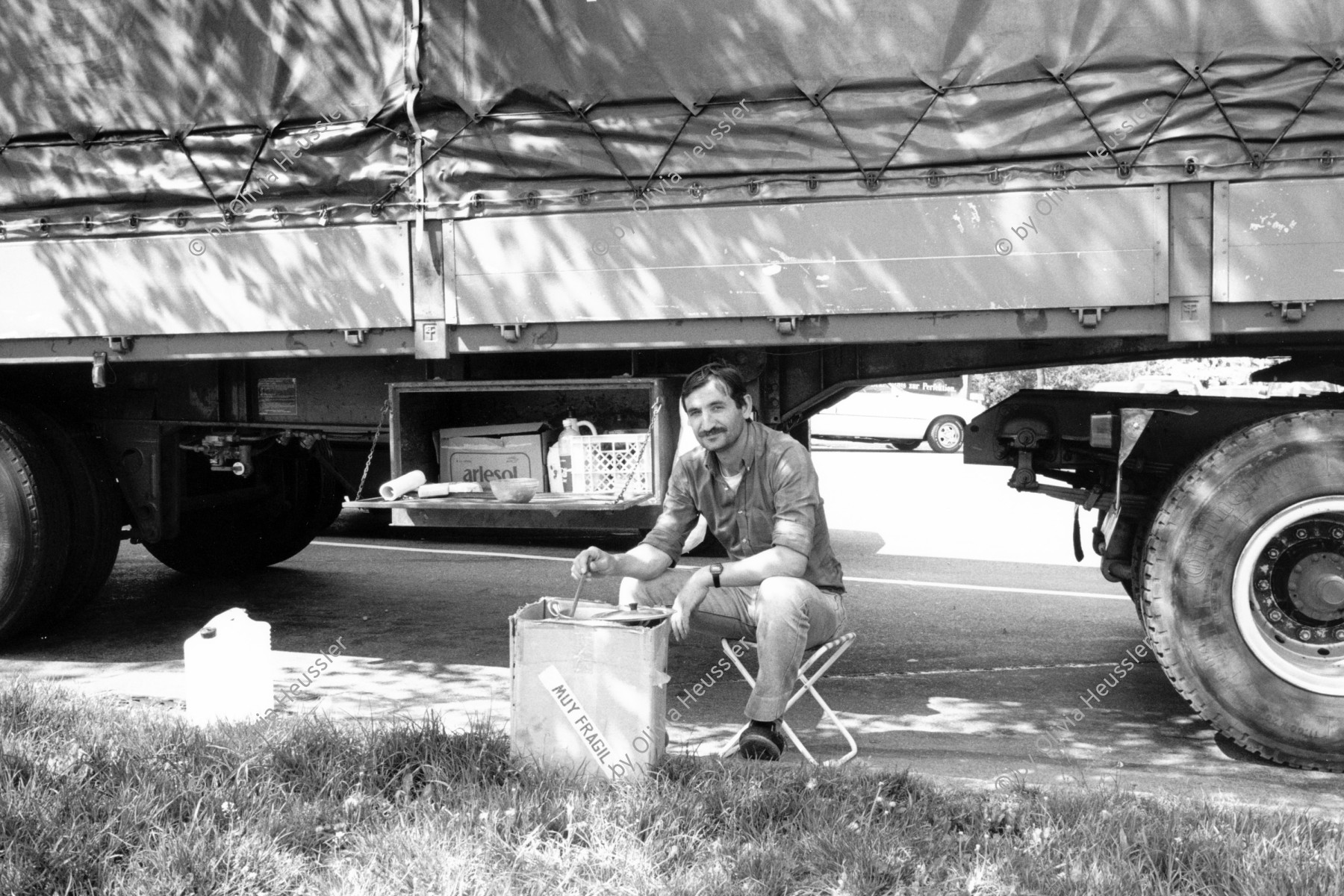 Image of sheet 19900390 photo 26: A truck driver eating his lunch beside his truck. 1990