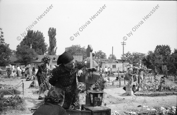 Image of sheet 19900410 photo 11: Kinder spielen mit 'Gondel' in Wohnsiedlung. Soldaten, Mütter und Väter etc.  legen auf einem neuen Friedhof für ihre gefallenen Freunde u/o Brüder und Söhne Blumen nieder. Wachsresten. Flugzeug Propeller Flügel. Portrait Susan und Judith (ihre Tochter) Hotel in Sibiu gebaut von Sohn Cheaucescu's. Edel Restaurant. Kind malt auf Strasse mit Kreide. Vater und Kind (im selbstgebastelten Kinderwagen). Markt. Rumania Romania 1990