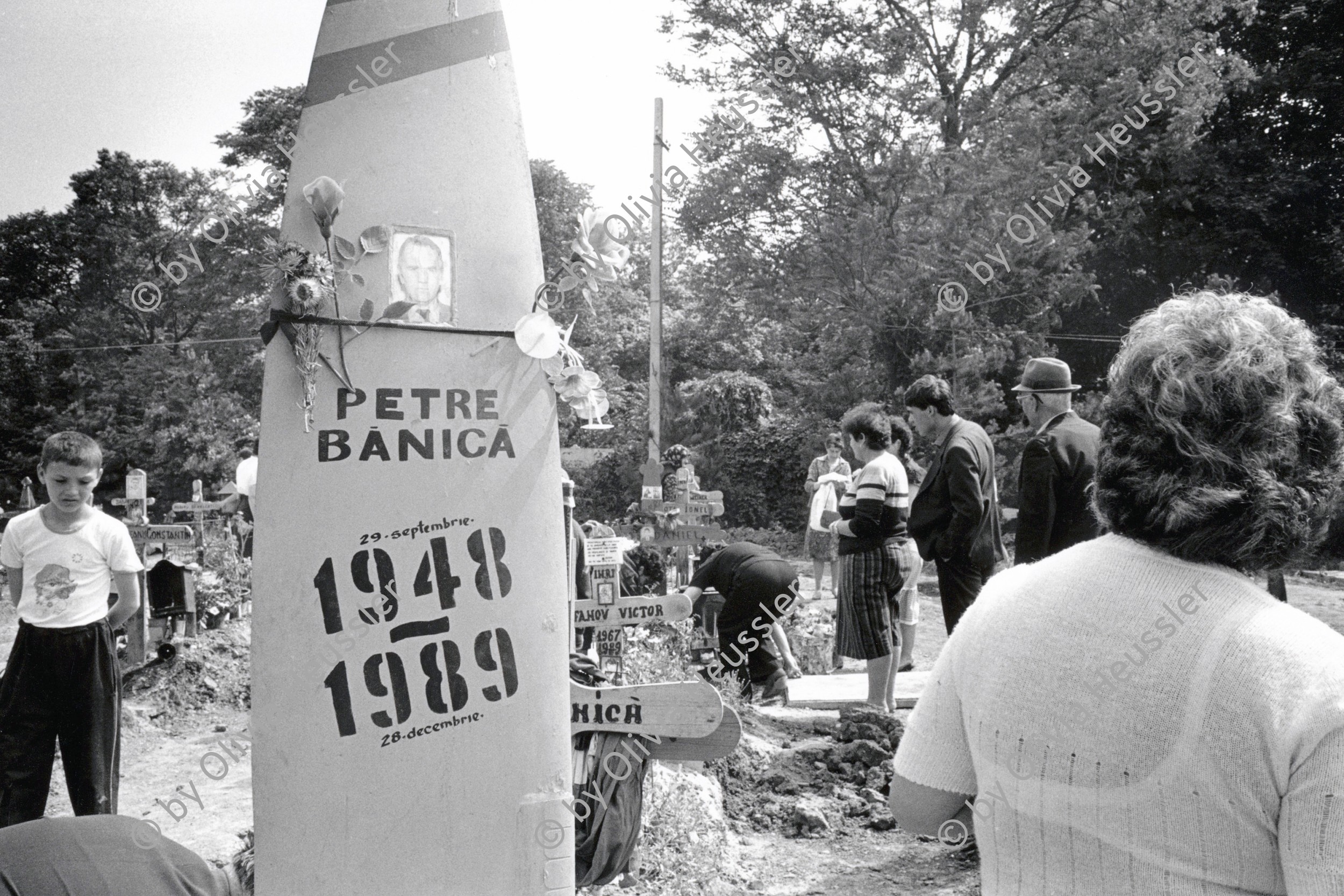 Image of sheet 19900410 photo 13: © 1990, OLIVIA HEUSSLER / www.clic.li
Angehörige Familie, Soldaten, Mütter und Väter etc.  legen auf einem neuen Grab Friedhof für ihre gefallenen toten Freunde u/o Brüder und Söhne Blumen nieder. Wachsresten. Flugzeug Propeller Flügel. als Grabstein. Rumänien bei Bukarest Rumania Romania 1990  √