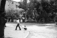 Image of sheet 19900410 photo 18: Kinder spielen mit 'Gondel' in Wohnsiedlung. Soldaten, Mütter und Väter etc.  legen auf einem neuen Friedhof für ihre gefallenen Freunde u/o Brüder und Söhne Blumen nieder. Wachsresten. Flugzeug Propeller Flügel. Portrait Susan und Judith (ihre Tochter) Hotel in Sibiu gebaut von Sohn Cheaucescu's. Edel Restaurant. Kind malt auf Strasse mit Kreide. Vater und Kind (im selbstgebastelten Kinderwagen). Markt. Rumania Romania 1990