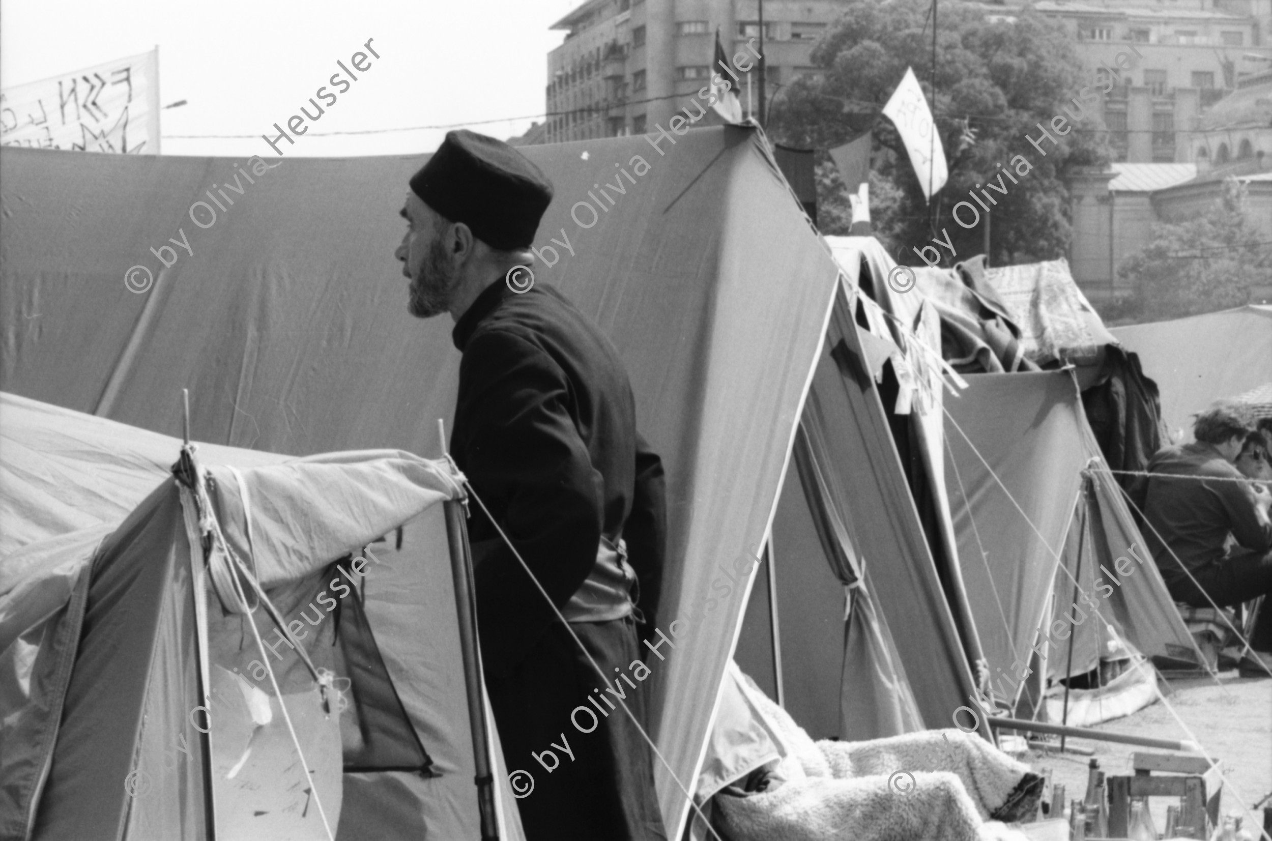 Image of sheet 19900440 photo 13: Supermarkt, Judentum jüdisch geschlossene Synagoge, Jos Comunism=Kein Komunismus. Religiöse Golanis auf dem Universitätsplatz protestieren gegen die Regierung von Ion Iliescu vom FSN 
Golani=Vagabunden Illiescu hat sie so genannt. Zeltlager der Golani auf dem Universitäts Platz. Frau schläft neben Zelt. Bukarest Rumänien, Romania, Rumania, 1990 

Psychiatrische Klinik in Zärnesti. Frauen Portrait. Frauen liegen im Bett, eine liest. Die 23 jährige Blanca Mihai sagt: 'Ich bin eine Roma. Der Name kommt aus dem Sanskrit und heisst: Eine Person, die zu unserer Gruppe gehört. Ich habe drei Jahre als Strassenputzerin für die Stadt gearbeitet. Eine Angehörige meiner Kollegin hat mir die Arbeit weggenommen. Jetzt bin ich krank und lebe hier unter alten Menschen'.

The National Salvation Front (Romanian: Frontul Salvării Naţionale, FSN) was the governing body of Romania in the first weeks after the Romanian Revolution of 1989, subsequently turned into a political party. FSN is the common root of two of the three largest political parties in Romania today: the Social Democratic Party (PSD) and the Democratic Liberal Party (PD-L).