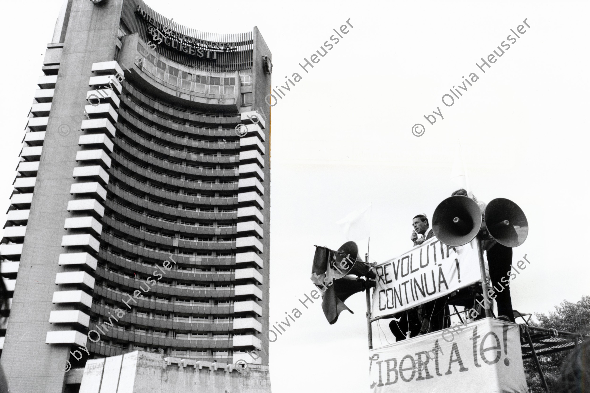 Image of sheet 19900510 photo 17: Vor dem Hotel 'Intercontinental Bucuresti' spricht ein Mann vor Lautsprechern an die Masse. Nach den Wahlen geht 'die Revolution' weiter. 'Libertate' Revolutia continua!' Bucarest Bukarest Rumänien 05.90 1990  Romania Rumänien Rumania √
after the first elections after 40 years. 
democratical demokratie process prozess