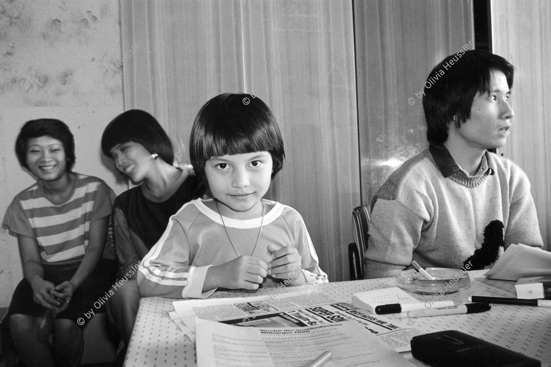 Image of sheet 19900681 photo 36: Mädchen in der Beratungsstelle für Vietnamesische Arbeitnehmer*Innen und Vertragsarbeiter, Berlin Marzahn 1990.
Nguyen Luu Huong Quang, mit seiner Tochter. 1143 Berlin Marzahn Schorfheidestr. 6/0203. Postadresse: Tamara Hentschel (Beyreiss) Belziger Ring 21/0604 1143 Berlin Marzahn Nord. Berlin former GDR
 engl.
Nguyen Luu Huong Quang with his daughter is sitting in his information office for Vietnamese workers in East Germany. Quang built up this information office without any help from the East-German state. Apart from this job he is also a considerate father and looks after his daughter.
√ 1990