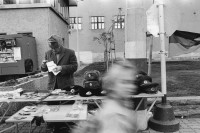 Image of sheet 19900720 photo 6: Nach der Wende verkaufen Leute aus dem Osten altes Militärmaterial am ehemaligen Checkpoint Charlie. DDR GDR Ost Ostberlin  Deutschland Ostdeutschland Berlin 1990 Military uniforms 
Former Chepoint Wallborder to Eas-Germany GFR. An old Polish Citizen is sitting near old military uniforms from various Eastern Countries. The Pole is selling thes uniforms to travellers who visit whatever is left over from the 'Wall'. √