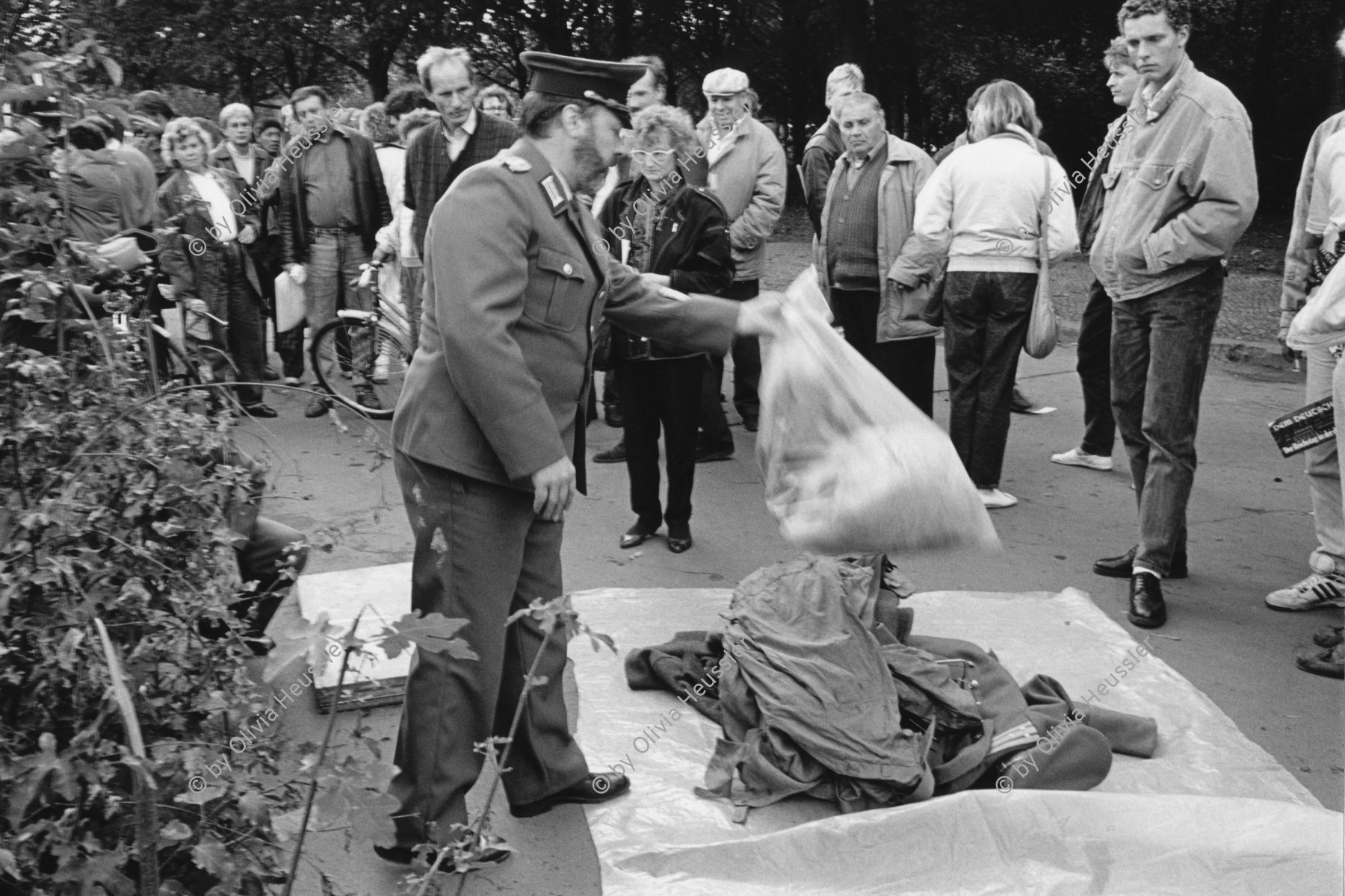 Image of sheet 19900730 photo 32: Ein Volkspolizist räumt die Waren eines Schwarzmarkthändlers aus Polen weg, Berlin zwischen Reichstag und Brandenburgertor, 1990. 
Deutschland Germany GDR DDR Policeman Market Markt Business shop street