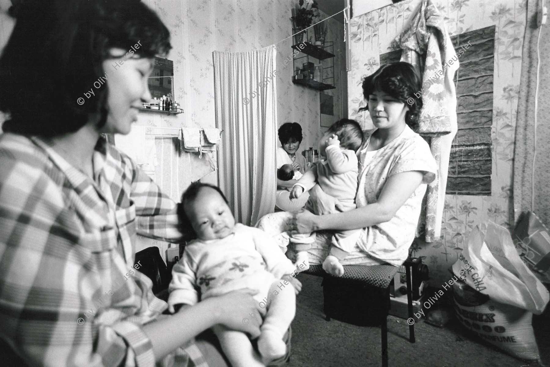 Image of sheet 19900770 photo 18: Vietnamesische Vertragsarbeiterinnen mit ihren Babys nach ihrer Entlassung, Berlin DDR vor der Wende, 28. September 1990.  Die Fremdarbeiter Vertragsarbeiter innen aus Vietnam, haben alle ihre Stelle verloren und die Väter ihrer Kinder sind verschwunden. 1.10.90 DDR kurz vor der deutschen Wiedervereinigung 1990 √ baby women woman care kleinkinder vietnamesinnen

Nguen Lan Anh (r) shares the room with two other young Vietnamese women ad their children babys. The three women all worked for the people owned mens clothing industry factory in Eastgermany, a firm called 'Fortschritt' (Progress). 
© 1990, OLIVIA HEUSSLER / www.clic.li