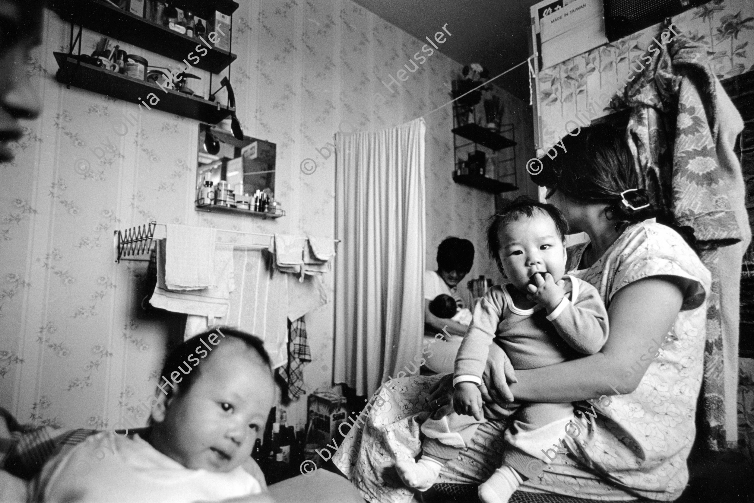 Image of sheet 19900770 photo 20: Vietnamesische Vertragsarbeiterinnen mit ihren Babys nach ihrer Entlassung, Berlin DDR vor der Wende, 28. September 1990. Vietnamesische Fremdarbeiter Vertragsarbeiter Innen aus Vietnam als Textilnäherinnen in VEB Fortschritt Herrenbekleidung tätig. Im Wohnheim an der Rhinstrasse 91 D,Zimmer 5, Berlin 1136 Friedrichsfelde Ost. mit ihren Kleinkindern. Sie wohnen zu dritt mit ihren Kindern im selben Zimmer , abgetrennt mit Vorhängen. Die Väter der Kinder sind unbekannt. Die Frauen werden alle ausgeschafft.
 
 their work-situations as well as information on possibilities to
 learn German, was very high. The general situation has worsened during the last months due to massdismisalles , because of measures seeking higher profits. The future of the Vietnamese industrial sewers for male clothing.
 working at the VEB Fortschritt is very unsure.As far as the living situation of these young mothers is concerned, they have to live on very little space and the cost of living is getting higher every day due to the political change.
Berlin Deutschland Germany 1990 √ baby women woman children 

© 1990, OLIVIA HEUSSLER / www.clic.li