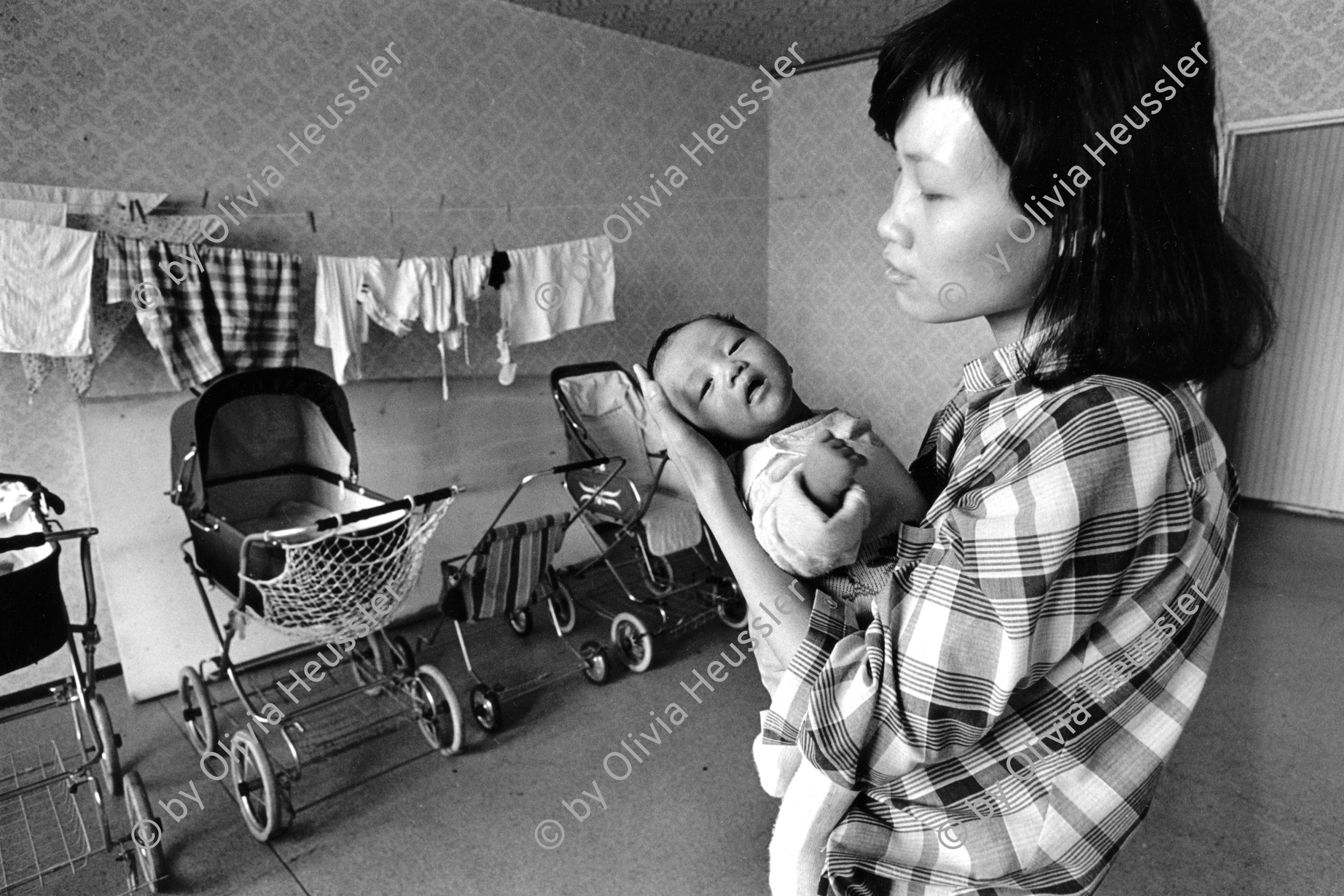 Image of sheet 19900770 photo 27: Nguyén Lan Anh (22) mit ihrem 2 Monate alten Söhnchen Nguyén Truong Long im Wohnheim für vietnamesische Vertragsarbeiterinnen an der Rhinstrasse in Berlin, vor der Wende, September 1990. 
Die Fremdarbeiter innen aus Vietnam, haben alle ihre Stelle verloren. Berlin Deutschland √ 01.Okt. 1990 woman vietnamese baby women refugee Kinderwagen baby trolley car mother
© 1990, OLIVIA HEUSSLER / www.clic.li