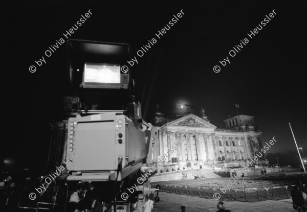 Image of sheet 19900790 photo 1: Der Reichstag in der Wiedervereinigungs Nacht. Durch TV Kamera. Jubelnde Menge am Brandenburger Tor. Nacht. 'Europa ohne Armee Deutschland zuerst 1914 1939 1990' Transparent. Helm und Schaf Maske. Portrait Larry Boyd in Berlin. Polizei kontrolliert und durchsucht  Demonstranten Innen gegen Wiedervereinigung. Grenadiere Transparent 'Gegen Rassismus und Grossdeutschland. 
Young left-winged activist is covering his face with his hand to keep his identity from whoever tries to take pictures from him. This reaction is the consequence of continuing police control in Berlin s streets. Especially as there is also a Anti Reunification Movement in Berlin Deutschland 1990