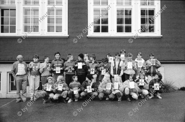 Image of sheet 19900930 photo 10: frtsg. 900920 Schulklasse spielt vor Schulhaus auf Pausenhof. Gruppenbild jedes Kind trägt die Flagge Fahne seines Herkunftsland. Eine Türkin etc. Primarlehrer Primarschule Lehrer Thöny vor seinen Photographien. 5 und 6. Klasse. Buben mit typischem Appenzeller Ohrschmuck. Urnäsch im Kanton Appenzell Ausserrhoden