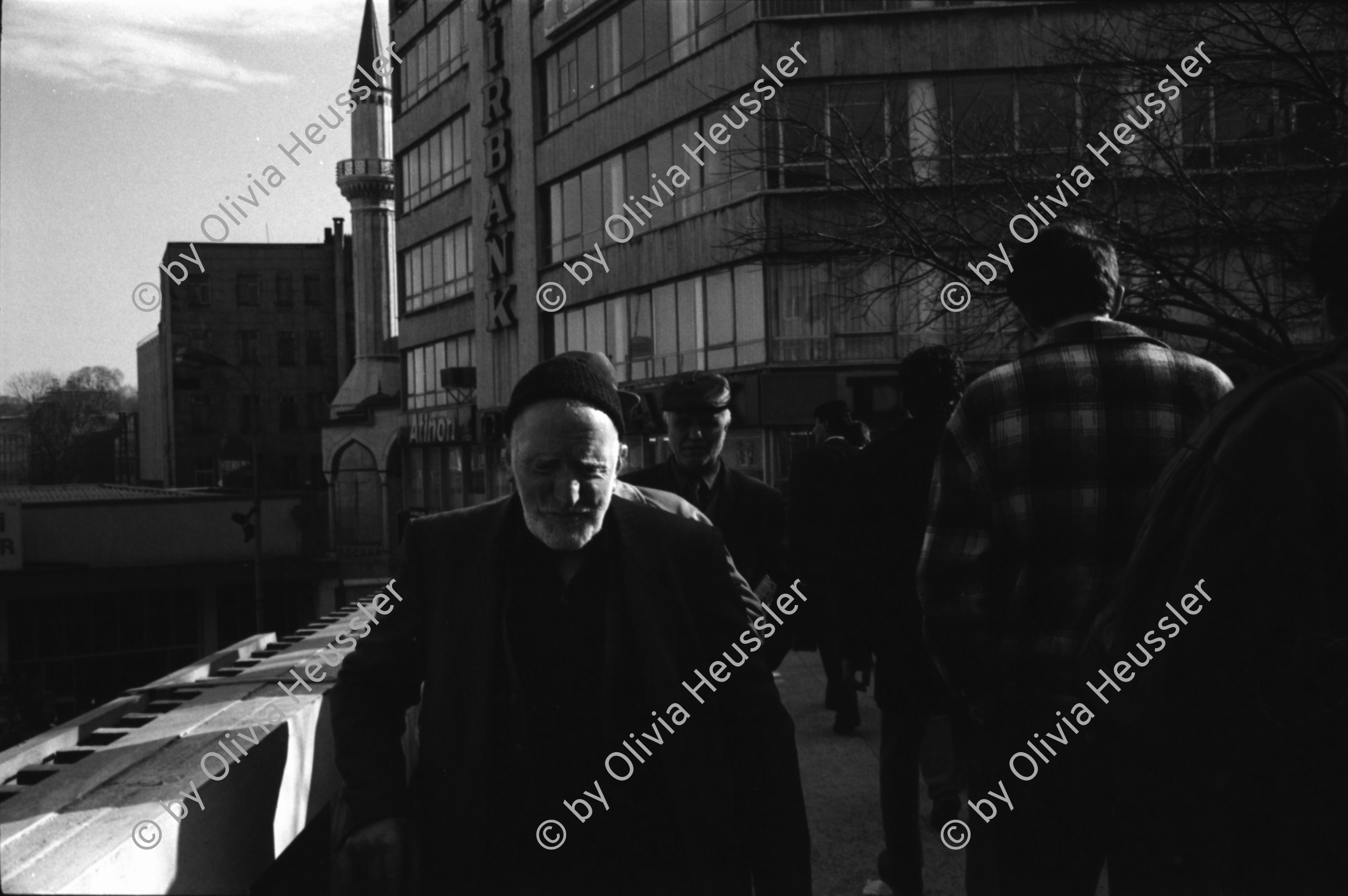 Image of sheet 19900960 photo 17: Strassenszenen Moschee. zwei alte Männer. Nikon Tafel. Bahnhof. Schnurrbart Schnautzmänner Schaufenster. Kebab Stand. Ein muslimisch fundamentalistisches Paar. Briefkasten und Kinder. Mann schleppt grosse Ladung auf Rücken. Bulgarinnen kaufen ein. Junge Gruppe Schulkinder. Spiegelungen. 1990 Türkei Istanbul