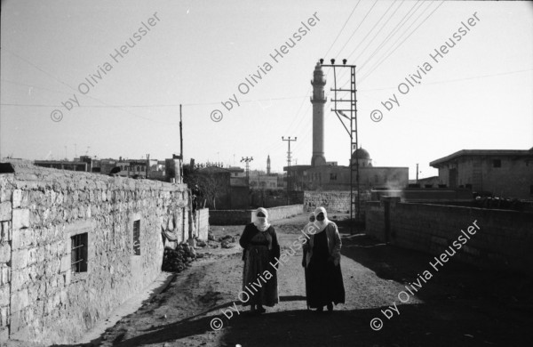 Image of sheet 19901030 photo 21: Dr. Karaman leitet als Arzt den Menschenrechtsverein in Nusaybin. Atatürk wacht auch über ihn und den Knaben.Bei der weissen Quelle auf dem Weg nach Seyhmehmet.Bauern Frauen waschen grosse Bleche am Fluss. Eine Frau trägt einen Kanister auf der Schulter. Sie trägt einen Schlüssel am Rock, was besagt, dass sie die Herrin im Haus ist und oder den Schlüssel zum Paradies besitzt.Kindergruppe. Mann pflügt mit Pferd den Acker. Am Postbüro PTT in Midyat kleben politische Propaganda Plakate gegen die PKK. Ein Schulhof, mit Atatürk s Siluette. Drei Frauen. Kohl wird ausgeladen. Die Frau schleppt und der Mann lächelt. Turkish Kurdish Kurdistan Kurds