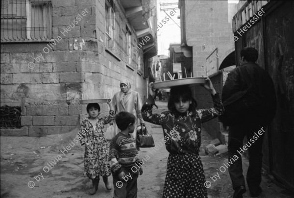 Image of sheet 19901060 photo 11: Diyarbakır (Diarbekir, osmanisch ‏دیاربکر‎ Diyâr-i Bekr, „Land von Bekr“, zazaisch und kurdisch Diyarbekir bzw. Amed, griechisch Ἄμιδα und syrisch-aramäisch (Amed) bzw. (Amid) (Amida), armenisch Ամիդա) ist mit 843.460 Einwohnern (Stand Ende Dezember 2010) nach Gaziantep die zweitgrößte Stadt Südostanatoliens. Diyarbakır liegt auf einem Basaltplateau am rechten Tigrisufer in Südostanatolien.

Knaben auf einem Esel. Ein Durchgang durch die alte Stadtmauer. Es geht eine muslimische Fundamentalistin vorüber. Ein Knabe kommt mir entgegen. Spiegelung eines Brotverkäufers in einer Pfütze. Kinder spielen in einer alten Hausfassade einer Ruine.Peschmerga.transportieren Getreide. Totenkopf an der Wand. Koran Schule für Knaben. Durch Gitter hindurch. Knabe verkauft bretzeln. Im Beifahrer wagen liegt ein Totes Gefieder. Am Markt. Knaben verkaufen Süssspeisen und tragen die Bleche auf dem Kopf. Diyarbakir Kurden 
Kurdische Türkei Kurden Turkish Kurds Turkey Kurdish 1990