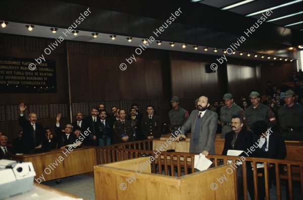 Image of sheet 19903006 photo 21: Im Staatsgericht Ankara. Der Prozess um den kurdischen Anwalt Vedat Aydin Nr. 5, der im Juli 91 von Todesschwadronen umgebracht wurde. Im Prozess wurden alle drei wegen Kurdisch sprechens verklagt, und später frei gesprochen. Mi: Ahmet Zeki Okçuoğlu, und re: Mustafa Oezer (HEP). In der Anklagebank. Umringt von türkischen Militärs. Die Verteidiger Innen, über 100, zogen sich unter Protest zurück und führten später ihre Plädoyer aus dem Zuschauerraum. Turkey Kurdish Kurds Die angeklagten kurdischen Anwälte v.l.n.r. Vedat Aydin, (Vedat Aydın, the Diyarbakır branch chairman of the now-defunct People’s Labor Party (HEP), was found dead on a road near Malatya on 7 July 1991, two days after armed men had taken him from his home in Diyarbakir.