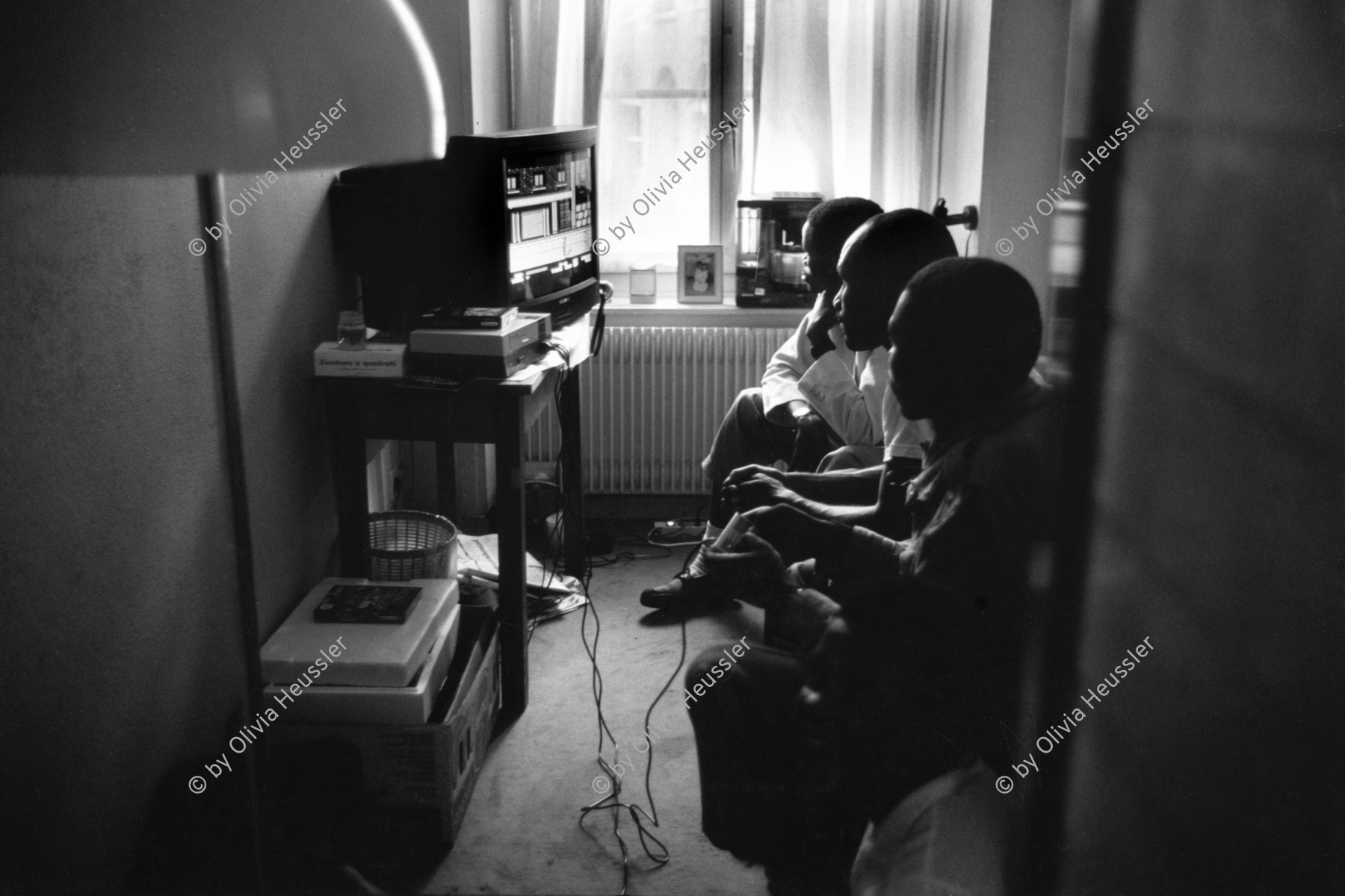 Image of sheet 19910182 photo 32: Afrikanische Flüchtlinge spielen in einem Zürcher Hotel Hirschen Video Games. Zürich Niederdorf √ refugees migration imigrants african black Switzerland Swiss 1991 watching tv media television in a hotel downtown