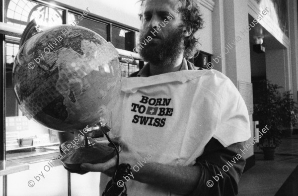 Image of sheet 19910231 photo 7: Der südamerikanische Fotograf John Liebenberg (1958 - 2020) hat Probleme mit dem Bahnpersonal, Schweiz 1991. Als Weltbürger kauft er eine Weltkugel. T-Shirt Born to be Swiss. Bahnhof. Gepäck In der Bahn hängt ein Photo von Johns Texte hängen auch da es sind Liebesgedichte an mich. Kanton vaud waadt Schweiz Suisse Switzerland 1991 Photographer Photography