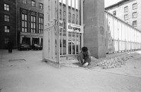 Image of sheet 19910510 photo 33: frtsg. 910500 ehem. Reichsluftfahrtministerium, Haus der Ministerien DDR, Treuhandanstalt und heute Bundesfinanzamt an der Wilhelmstrasse in Berlin.
Eingang Türkischer Fremdarbeiter legt Pflästerer Pflastersteine. Olivia. 
A Turkish worker is setting paving-stones in front of the German trust-company whilest an employee of the company is leaving the area of the firm. The German trust-company got its reputation due to its job, having to integrate firms of Eastgermany GDR into the Western capitalist economic system. 1991 Berlin Germany Deutschland DDR