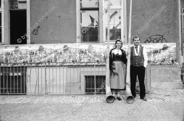 Image of sheet 19910810 photo 28: Portrait Spielplatzanimation Kreis 4 vier Kanzleischulhaus. Alphornbläser Alphorn und Paar in Tracht in der Kanzleiturnhalle anlässlich der ' Schwinget Schwingen 
Aussersihl 1991 Zürich Schweiz Switzerland

© 1991, OLIVIA HEUSSLER / www.clic.li