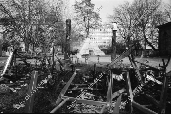 Image of sheet 19920010 photo 24: Flohmarkt im Kanzleischulhaus. Silvano Speranza fährt den Federlos Bus. Züglete vom Kanzlei. Plastik von Schang Hutter. Werbeplakat für Baer gescrached. Schulbänke liegen im Hof verbrannt. Rebecca Naldi. Schulhaus Portrait Kanzleischulhaus und brennende Schulbänke. Zürich 1992 pulte tables chairs burned fyer schule school 
housing occupation occupied house home protest swiss switzerland Schweiz Europe