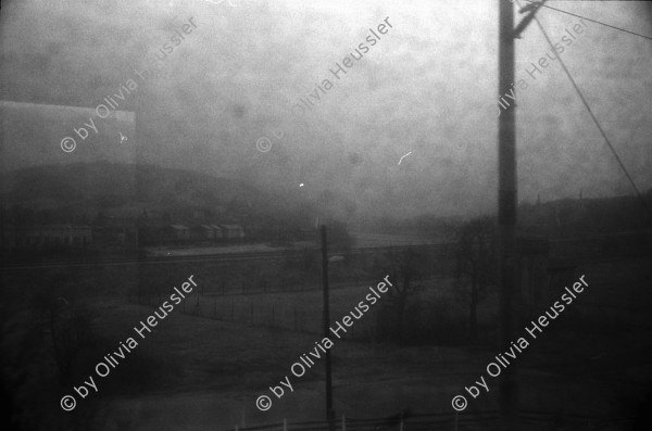 Image of sheet 19920080 photo 1: Der Fluss Elbe durch schmutziges Fenster. Es stehen Rucksäcke am Bahnhof von Usti mit Snackbar und sog. Pfadfinder oder eine Jugendgruppe. weibl. Bahnangestellte. Kohlebergwerk von Most. Mit Kirche. die auf Schienen früher weg transportiert wurde. Zug reihe. Wagons Tagabbaugebiet für Braunkohle Richtung Karlsbad, dem Erzgebirge entlang. Norden Tschechien Jirkov Bahnhof. Nordböhmen ehemaliges Sudetenland. Nach dem zweiten Weltkrieg wurden die mit Nazi Hitler sympatisierenden Sudeten, die deutsch sprachen, mit gerade 20kg Gepäck pro Person, ausgeschafft. Usti. Czech Republic. 1992