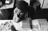 Image of sheet 19920160 photo 0: Chinwe Speranza aus Zimbabwe steht mir Modell für eine Arbeit fürs FIZ zum Thema Frauen aus der dritten Welt im Konflikt mit dem Schweizerischen Strafgesetz. Bücher Justiz etc. Sie ist nicht zu erkennen. hat oft Augen mit Hände verdeckt. Hände auf Bücher. Das Schweizerische Zivilgesetzbuch. Zürich 1992