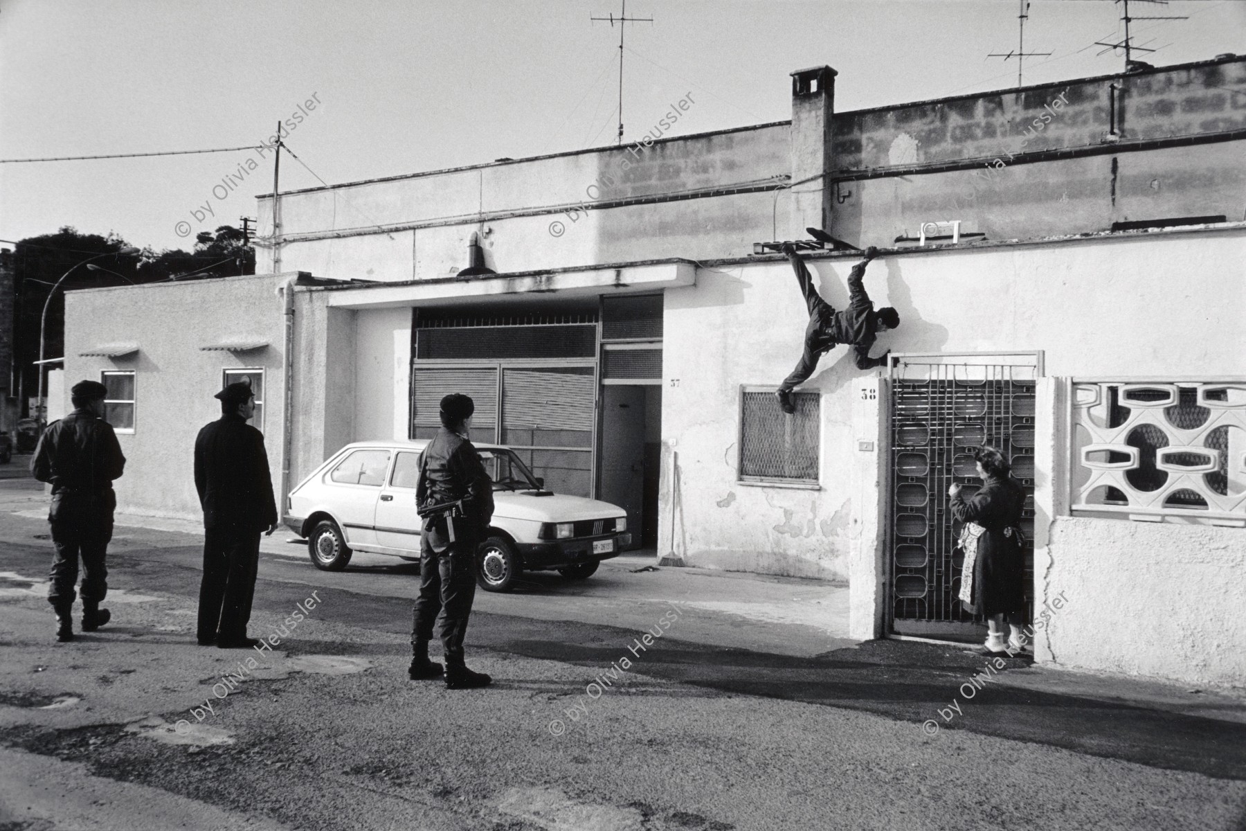 Image of sheet 19920220 photo 20: Ein Armeeangehöriger Soldat Militär Carabinieri Polizei zeigt während einer Razzia im Schmuggelquartier 'Il Paradiso' seine Künste beim Fasadenklettern. Brindisi, Italien Italy Razzia 03.92 1992 √
Schmuggler Schmuggeln smuggler