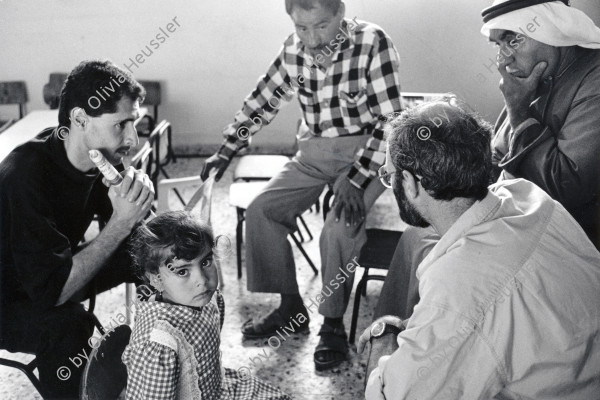 Image of sheet 19920410 photo 0: Der israelische Arzt, Ralf Guggenheim betreut in den mobilen Kliniken, ein palästinensisches, herzkrankes Mädchen, Anabta, Palästina 1992. 
The jewish Israeli doctor Ralf Guggenheim treats a girl with heart problems in the mobile clinic, organized by the AIPPHR. Anabta. 1992 √ Human rights health care
take care of little medical problems health days center ngo occupied territory hard men father old man kuffiah palestinian
Aus: Out of Jerusalem / Jenseits von Jerusalem page 71