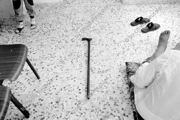 Image of sheet 19920430 photo 3: Ein gehbehinderter Mann wartet zu Hause auf die Hauskrankenpflegerin. Beit Suriq, Westbank. Palästina. 05.92 1992 √ Gehstock stock beine legs chairs feet old man medical asistant care Beine
From:  Out of Jerusalem / Jenseits von Jerusalem page Nr. : 51
Physically handicapped patient waiting for a nurse in his house.

handicapped old man is waiting for Etimad, a young Palestinian physical therapist. occupied territory Palestine 1992
Art-Collection City of Bienne, CH

Exhibition
Out of: From time to time  / Von Zeit zu Zeit
ohne Aufkleber