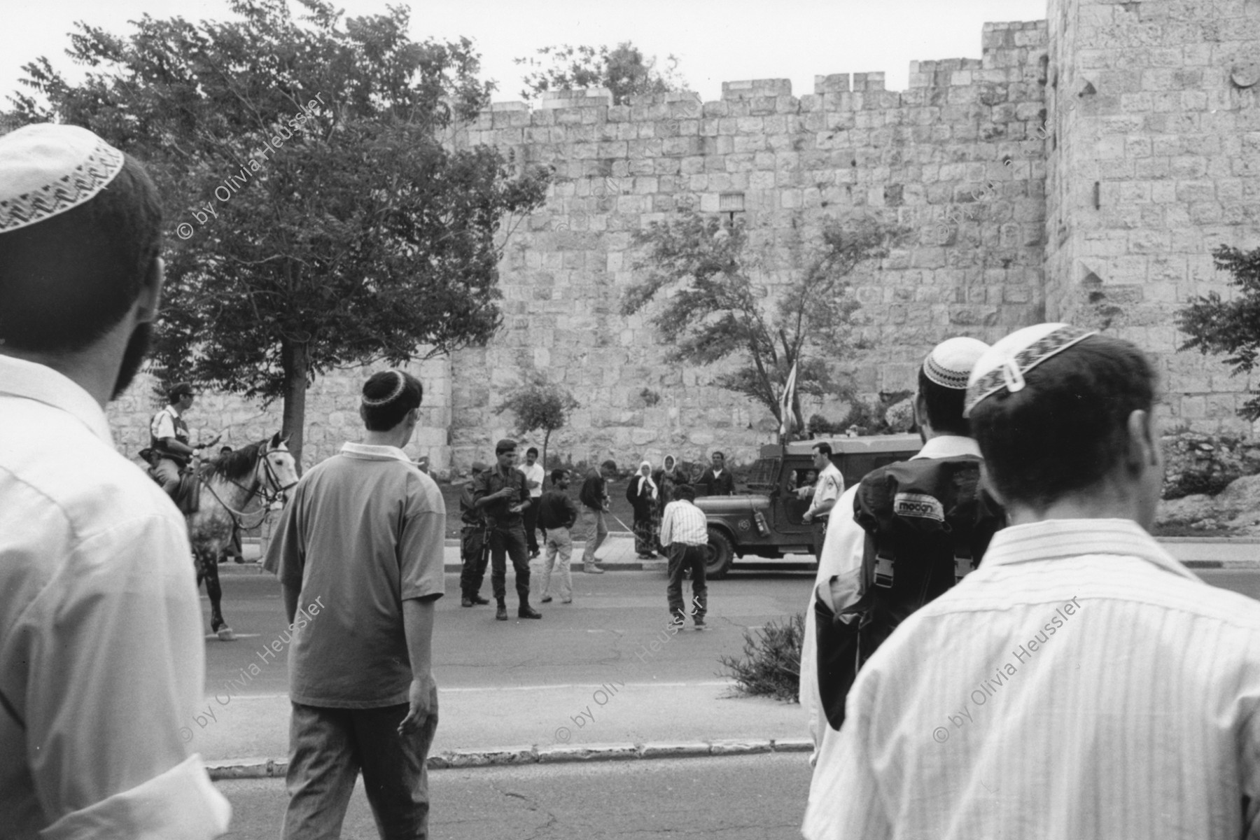 Image of sheet 19920430 photo 33: © 1992, OLIVIA HEUSSLER/ www.clic.li
Eine Armee patrouillie  kontrolliert den Strassenverkehr vor dem Herodes Tor in Ost-Jerusalem, während junge religiöse Israelis zuschauen. jewish religous kippa kipah

army patrol controls the traffic in front of Herod's Gate in East Jerusalem while young religious Israelis watching. Israel Palestine 1992 √