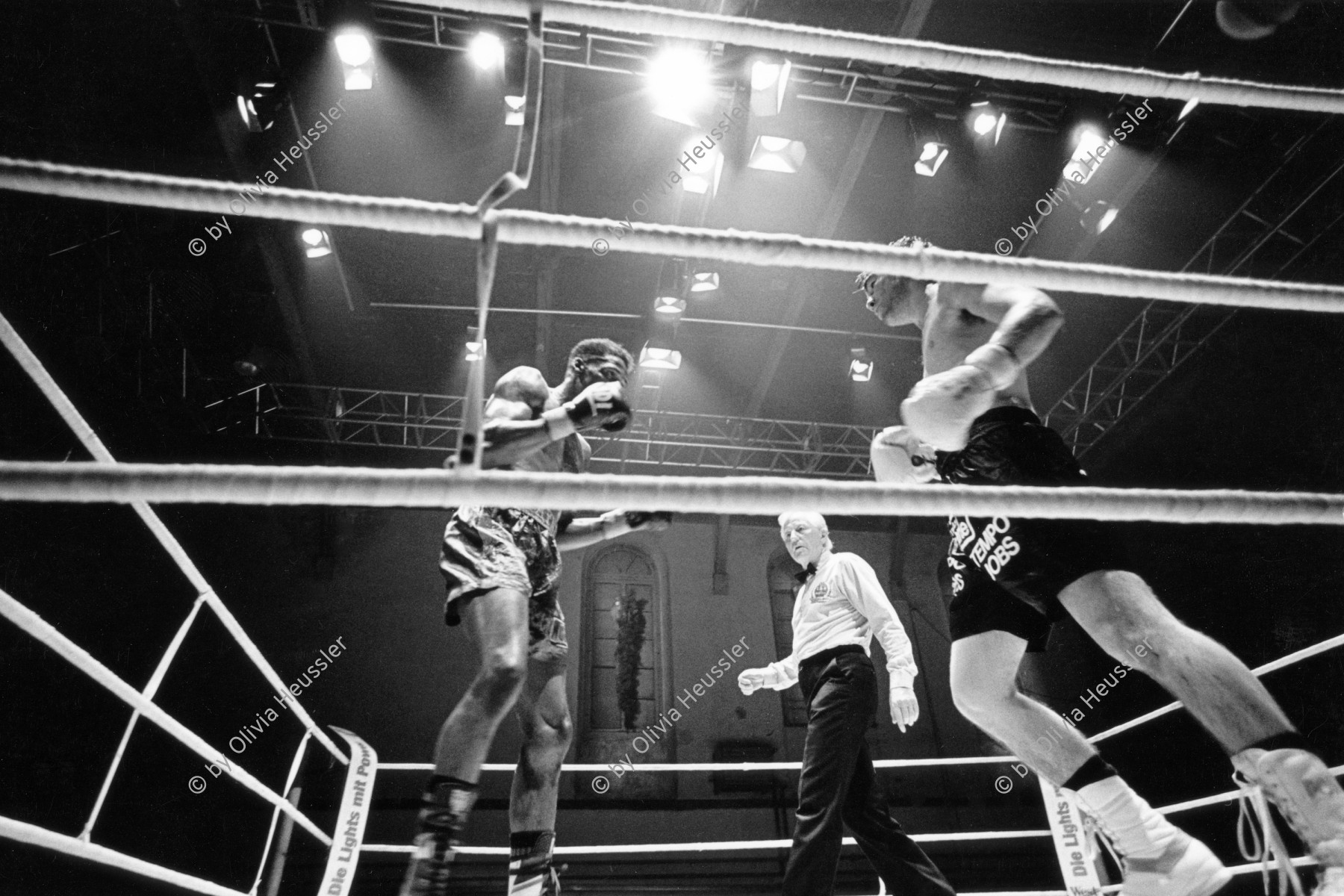 Image of sheet 19920500 photo 35: Der Berner Jean Charles Meuret und der Amerikaner Ricky Hayes beim Schwerwelter Gewicht Profi Boxmatch in der Gessnerallee in Zürich 1992 √ boxing sport heavy weight boxer Swiss Switzerland Europe american schiedsrichter
referee
Boxing (pugilism, prize fighting, the sweet science or in Greek pygmachia) is a martial art and combat sport in which two people engage in a contest of strength, reflexes, and endurance by throwing punches at an opponent with gloved hands