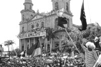 Image of sheet 19930380 photo 34: Menschenmassen Protest Demonstration Jubeln Feier am 19.7.93 auf der Plaza de la Revolucion, vor der Cathedrale Kathedrale:  Managua  ( 14. Jahrestag der sandinistischen Revolution ) FSLN Nicaragua  1993 √  19. Juli 1993
'Muerte al Somocismo' Steht auf dem Banner. Sandinistische flaggen und Fahnen. Clown mit Perrücke 

Durante las celebraciones del 14° aniversario
de la Revolución sandinista. Plaza de la Revolución, Managua, 19 de julio de 1993
Celebrating the 14th anniversary
of the Sandinista revolution.
Plaza of the Revolution, Managua, 1993

Die Kathedrale Santiago de Managua ist die Ruine der alten Kathedrale von Managua. Sie befindet sich an der Plaza de la Revolution, vormals Plaza de la República. Sie wurde als kaschierter Stahlskelettbau im neoklassischen Stil errichtet. Die Fassadenaufteilung ist ähnlich der von St-Sulpice de Paris.