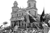 Image of sheet 19930380 photo 36: Menschenmassen Protest Demonstration Jubeln Feier am 19.7.93 auf der Plaza de la Revolucion, vor der Cathedrale Kathedrale: Managua ( 14. Jahrestag der sandinistischen Revolution ) FSLN Nicaragua 1993 √ 19. Juli 1993
'Muerte al Somocismo' Steht auf dem Banner. Sandinistische flaggen und Fahnen. Clown mit Perrücke

Durante las celebraciones del 14° aniversario
de la Revolución sandinista. Plaza de la Revolución, Managua, 19 de julio de 1993
Celebrating the 14th anniversary
of the Sandinista revolution.
Plaza of the Revolution, Managua, 1993
Die Kathedrale Santiago de Managua ist die Ruine der alten Kathedrale von Managua. Sie befindet sich an der Plaza de la Revolution, vormals Plaza de la República. Sie wurde als kaschierter Stahlskelettbau im neoklassischen Stil errichtet. Die Fassadenaufteilung ist ähnlich der von St-Sulpice de Paris.