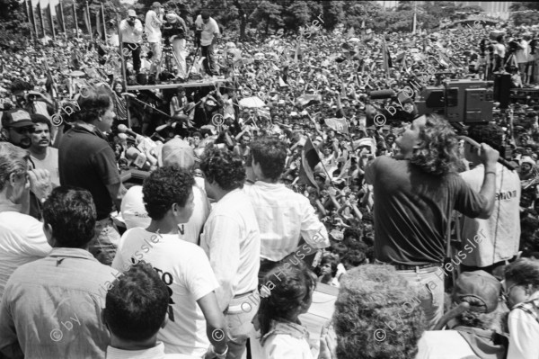 Image of sheet 19930400 photo 1: frtsg. 930390 Portrait Cmdte. de la Revolucion sandinista Daniel Ortega. FSLN Transparent auf der Kathedrale 'Muerte al Somocismo'. Mejia Godoy Frauen und Männer von hinten marschieren. IFA Lastwagen auf Lada. Kathedrale von Obando y Bravo. FROC in Esteli.
Feierlichkeiten zum 14. Jahrestag der Revolution Nicaragua 1993

Menschenmassen Protest Demonstration Jubeln Feier am 19.7.93 auf der Plaza de la Revolucion, vor der Cathedrale Kathedrale: Managua ( 14. Jahrestag der sandinistischen Revolution ) FSLN Nicaragua 1993 √ 19. Juli 1993
'Muerte al Somocismo' Steht auf dem Banner. Sandinistische flaggen und Fahnen. Clown mit Perrücke

Die Frente Sandinista de Liberación Nacional (FSLN; deutsch Sandinistische Nationale Befreiungsfront) ist eine politisch links orientierte Partei in Nicaragua, hervorgegangen aus der gleichnamigen Guerillaorganisation, die am 19. Juli 1979 an der Spitze einer breiten Widerstandsbewegung die seit 43 Jahren bestehende Diktatur der Somoza-Dynastie unter Präsident Anastasio Somoza Debayle stürzte und daraufhin Nicaragua bis 1990 regierte. Mit Daniel Ortega stellt sie seit Januar 2007 wieder den Staatspräsidenten Nicaraguas.

Die Kathedrale Santiago de Managua ist die Ruine der alten Kathedrale von Managua. Sie befindet sich an der Plaza de la Revolution, vormals Plaza de la República. Sie wurde als kaschierter Stahlskelettbau im neoklassischen Stil errichtet. Die Fassadenaufteilung ist ähnlich der von St-Sulpice de Paris.