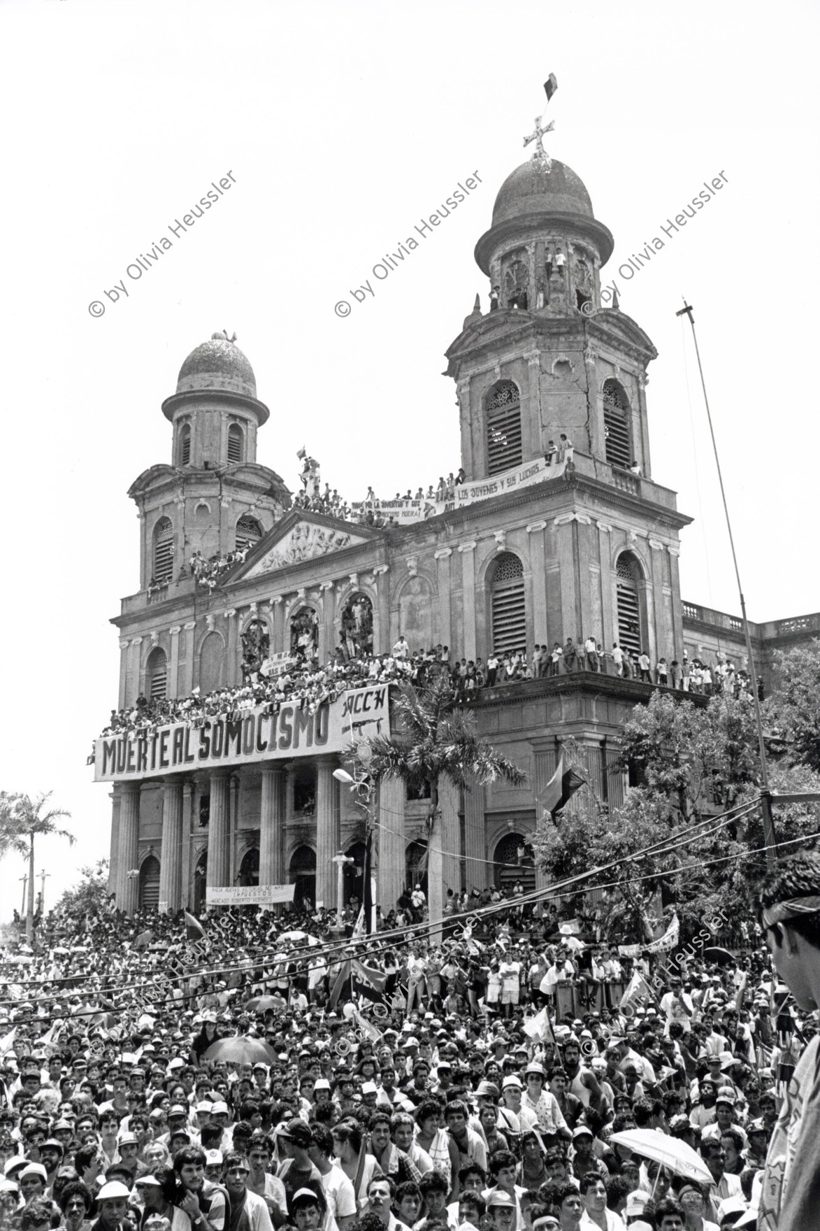 Image of sheet 19930400 photo 13: Während der Feierlichkeiten des 14 Jahrestages der sandinistischen Revolution in Managua am 19. Juli 1993 √
Menschenmassen Protest Demonstration Jubeln Feier am 19.7.93 auf der Plaza de la Revolucion, vor der Cathedrale Kathedrale: Managua ( 14. Jahrestag der sandinistischen Revolution ) FSLN Nicaragua 1993 √ 19. Juli 1993
'Muerte al Somocismo' Steht auf dem Banner. Sandinistische flaggen und Fahnen.

Durante las celebraciones del 14° aniversario de la Revolución sandinista. Plaza de la Revolución, Managua, 19 de julio de 1993
Celebrating the 14th anniversary of the Sandinista revolution. Plaza of the Revolution, Managua, 1993

Die Kathedrale Santiago de Managua ist die Ruine der alten Kathedrale von Managua. Sie befindet sich an der Plaza de la Revolution, vormals Plaza de la República. Sie wurde als kaschierter Stahlskelettbau im neoklassischen Stil errichtet. Die Fassadenaufteilung ist ähnlich der von St-Sulpice de Paris.