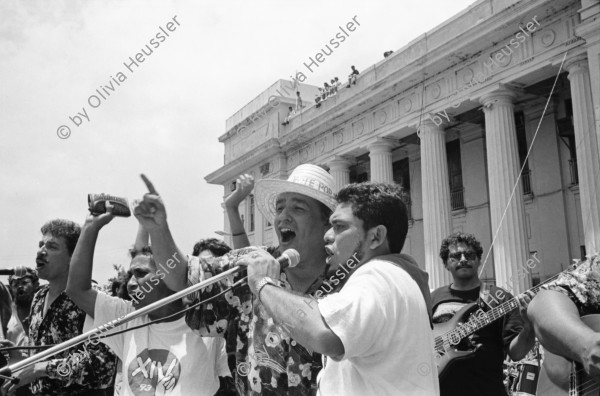 Image of sheet 19930400 photo 19: frtsg. 930390 Portrait Cmdte. de la Revolucion sandinista Daniel Ortega. FSLN Transparent auf der Kathedrale 'Muerte al Somocismo'. Mejia Godoy Frauen und Männer von hinten marschieren. IFA Lastwagen auf Lada. Kathedrale von Obando y Bravo. FROC in Esteli.
Feierlichkeiten zum 14. Jahrestag der Revolution Nicaragua 1993

Menschenmassen Protest Demonstration Jubeln Feier am 19.7.93 auf der Plaza de la Revolucion, vor der Cathedrale Kathedrale: Managua ( 14. Jahrestag der sandinistischen Revolution ) FSLN Nicaragua 1993 √ 19. Juli 1993
'Muerte al Somocismo' Steht auf dem Banner. Sandinistische flaggen und Fahnen. Clown mit Perrücke

Die Frente Sandinista de Liberación Nacional (FSLN; deutsch Sandinistische Nationale Befreiungsfront) ist eine politisch links orientierte Partei in Nicaragua, hervorgegangen aus der gleichnamigen Guerillaorganisation, die am 19. Juli 1979 an der Spitze einer breiten Widerstandsbewegung die seit 43 Jahren bestehende Diktatur der Somoza-Dynastie unter Präsident Anastasio Somoza Debayle stürzte und daraufhin Nicaragua bis 1990 regierte. Mit Daniel Ortega stellt sie seit Januar 2007 wieder den Staatspräsidenten Nicaraguas.

Die Kathedrale Santiago de Managua ist die Ruine der alten Kathedrale von Managua. Sie befindet sich an der Plaza de la Revolution, vormals Plaza de la República. Sie wurde als kaschierter Stahlskelettbau im neoklassischen Stil errichtet. Die Fassadenaufteilung ist ähnlich der von St-Sulpice de Paris.