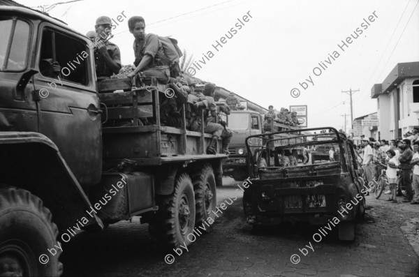 Image of sheet 19930470 photo 4: Das Militär (EPS) zieht in einem Konvoi aus Esteli ab Ein Paar in der Strasse. Frauen putzen die blut verschmierten Böden des Spitals. Angehörige suchen vermisste. Die ausgeraubte Bank. Teile der Barrikade. Auch die Bäume im Zentralpark Parque central sind mitgenommen von Einschusslöchern. Petroglyphen am Strassenrand. u.a. der Brujito. El Esteli Segovias Nicaragua 1993