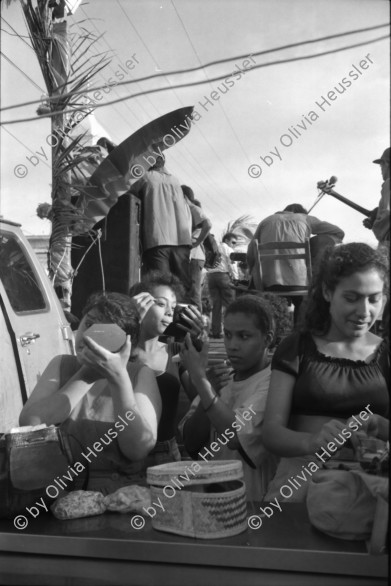 Image of sheet 19930521 photo 12: frtsg. 930520 Fiesta Santo Domingo. Frauen Tänzerinnen schminken sich. Junge Nicaraguaner sind von den Vereinigten Staaten zurückgekehrt. Heimkehrer aus den USA. Coca Cola Stand. Kids. Frau raffelt Guachada. Koch Banane.  Kirche von Santo Domingo mit Sateliten Pfanne am Kirchturm. Tänzerinnen. Apotheke Condega mit gemischten Waren Heilpflanzen sowie schulmedizinische Produkte. Nicaragua 1993 natural health medicine plants pharmacie