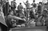 Image of sheet 19930521 photo 3: frtsg. 930520 Fiesta Santo Domingo. Frauen Tänzerinnen schminken sich. Junge Nicaraguaner sind von den Vereinigten Staaten zurückgekehrt. Heimkehrer aus den USA. Coca Cola Stand. Kids. Frau raffelt Guachada. Koch Banane.  Kirche von Santo Domingo mit Sateliten Pfanne am Kirchturm. Tänzerinnen. Apotheke Condega mit gemischten Waren Heilpflanzen sowie schulmedizinische Produkte. Nicaragua 1993 natural health medicine plants pharmacie