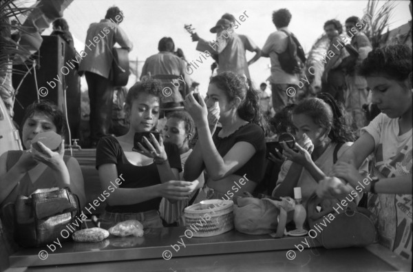 Image of sheet 19930521 photo 4: frtsg. 930520 Fiesta Santo Domingo. Frauen Tänzerinnen schminken sich. Junge Nicaraguaner sind von den Vereinigten Staaten zurückgekehrt. Heimkehrer aus den USA. Coca Cola Stand. Kids. Frau raffelt Guachada. Koch Banane.  Kirche von Santo Domingo mit Sateliten Pfanne am Kirchturm. Tänzerinnen. Apotheke Condega mit gemischten Waren Heilpflanzen sowie schulmedizinische Produkte. Nicaragua 1993 natural health medicine plants pharmacie