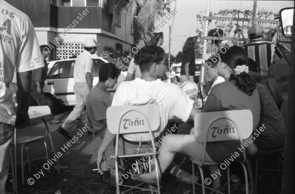 Image of sheet 19930521 photo 9: frtsg. 930520 Fiesta Santo Domingo. Frauen Tänzerinnen schminken sich. Junge Nicaraguaner sind von den Vereinigten Staaten zurückgekehrt. Heimkehrer aus den USA. Coca Cola Stand. Kids. Frau raffelt Guachada. Koch Banane.  Kirche von Santo Domingo mit Sateliten Pfanne am Kirchturm. Tänzerinnen. Apotheke Condega mit gemischten Waren Heilpflanzen sowie schulmedizinische Produkte. Nicaragua 1993 natural health medicine plants pharmacie