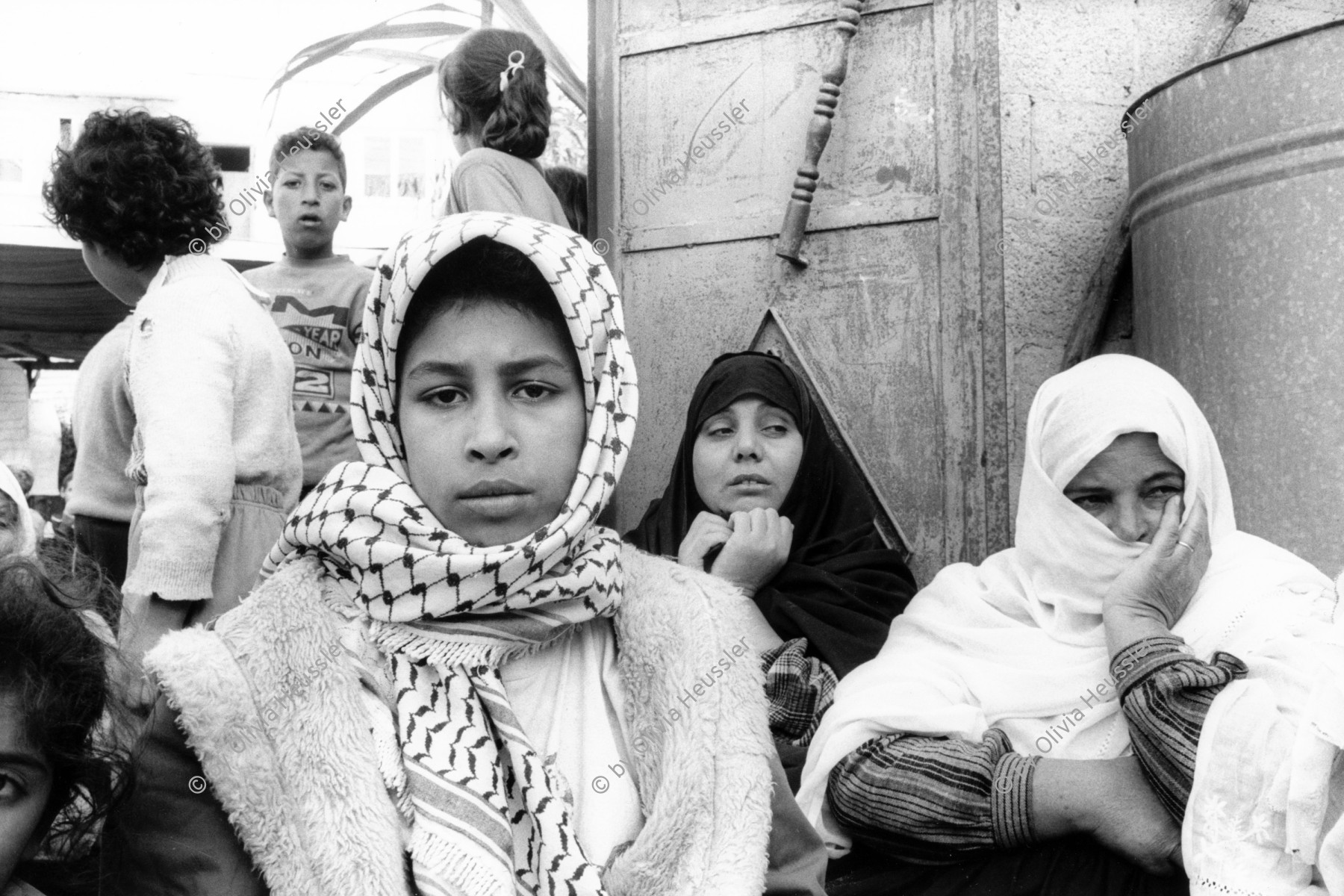 Image of sheet 19931240 photo 6: Frauen trauern um den Tod des Al Fatah Kaempfers, der nachdem er sich beim israelischen Militaer ergeben hatte, von diesem erschossen wurde, Khan Yunis, Gaza 1993. 

frtsg. 931240 Totenfeier bei Mutter von Abu Rish 2 und 3. Frauen sitzen um sie herum. Portrait. 30.11.
Women in sorrow with mother of killed Al Fatah fighter Abu Rish by Israeli army. Abu Rish was killed by a mistake after he desarmed. Khan Younis Gazastrip Palestine Nov. 1993 Mothers Gaza death women young mourns 

Khan Yunis Camp (Arabic: مخيم خان يونس‎, also spelled Khan Younis Camp) is a Palestinian refugee camp in the Khan Yunis Governorate just west of the city of Khan Yunis and two kilometers east of the Mediterranean coast in the southern Gaza Strip. While UNRWA states that there were approximately 72,000 Palestinian refugees living in the camp in 2010, the Palestinian Central Bureau of Statistics recorded a population of 37,705 in the 2007 census.


© 1993, Olivia Heussler √