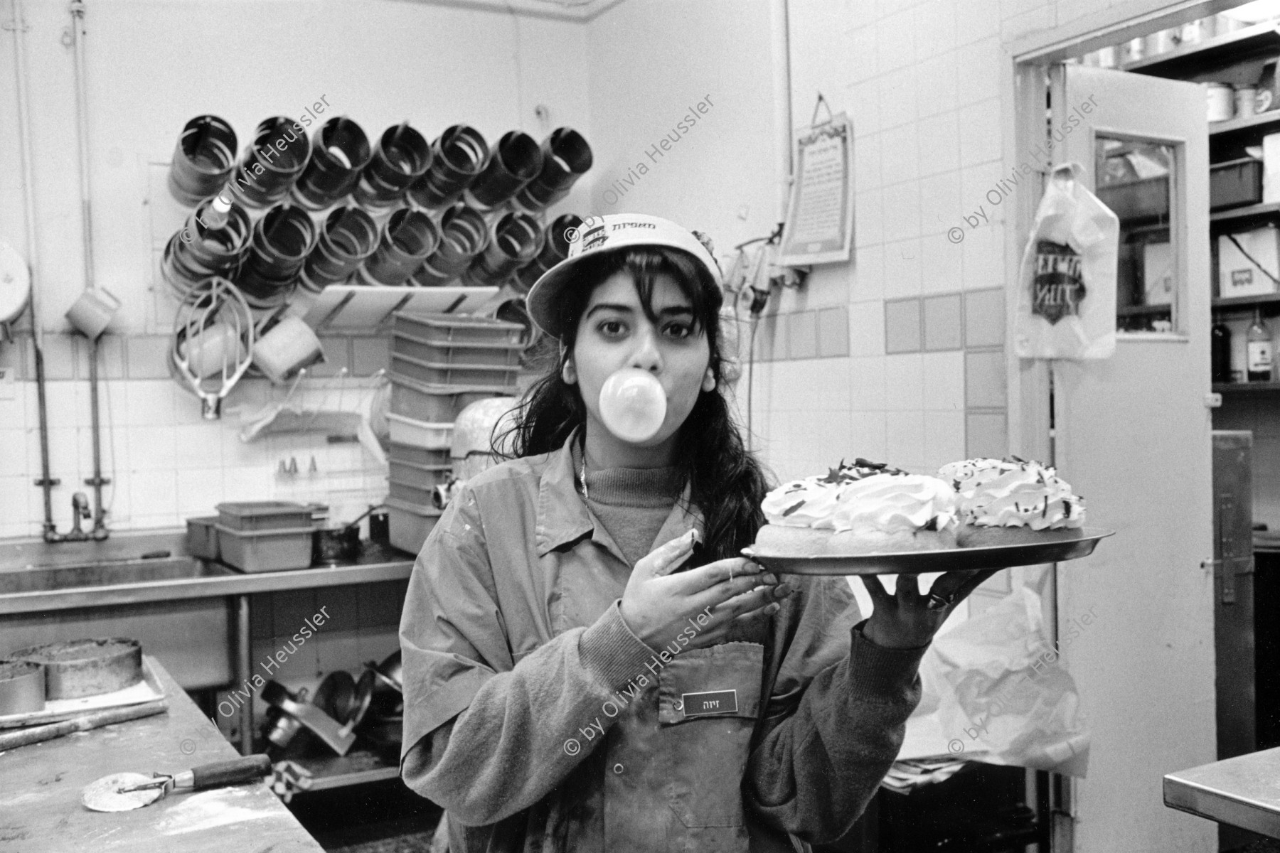 Image of sheet 19931320 photo 7: frtsg. 931310 Carol, 19 jährig arbeitet für NIS 7 und 6 Tagen plus Samstag Nacht in Angel's Bakery. Sie hat Militär gemacht und will jetzt Grafikerin werden. 
Carol, 19 , arbeitet nach dem Militärdienst in einer Bäkerei und verdient 7 NIS in der Stunde. (Schwarzmarktwechsel 1 US $ = 3 NIS) Israel West Jerusalem 1993 √ Women young worker woman work angels bakery shop Israeli Israel Palestine bread Kaugummi chewing gum
Carol, 19, former Military soldier in the Israeli army works after the military service, in a bakery and earns NIS 7 per hour
copyright by Olivia Heussler