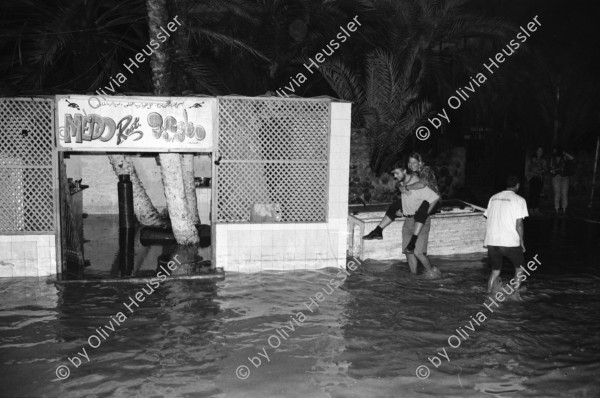 Image of sheet 19940010 photo 14: Englische touristen mit Beduinen. In Dahab gibt es nach starkem Regen
heftige überschwemmungen. Hochwasser. René Suter und Olivia Heussler mit Hotel angestellter im Hotelzimmer auf Bett, Matratze steht. Sinai ehemaliger Moshav Aegypten Egypt 1994 flood
Dahab (Egyptian Arabic: دهب or ذهب,IPA: [ˈdæhæb], gold) is a small town situated on the southeast coast of the Sinai Peninsula in Egypt. Formerly a Bedouin fishing village, located approximately 80 km (50 mi) northeast of Sharm el-Sheikh, Dahab is considered to be one of the Sinai's most treasured diving destinations. Following the Six Day War, the town was occupied by Israel and was known in Hebrew as Di-Zahav; named after a place mentioned in the Bible