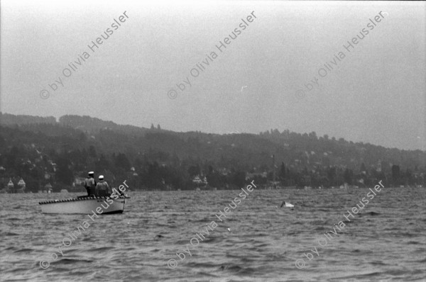 Image of sheet 19940340 photo 19: Polizeiaspirantinnen Polizei und Verkehrspolizisten beamte und Beamtinnen in Badehosen vor der Seeüberquerung Zürichsee Badi Wollishofen. 1600m nach Tiefenbrunnen. Nr. 0 -3 Herr Zurfluh Chef der Ausbildung. Ziel. Nr. 25 Fredi Bachmann Gewinner 32 Minuten. Schwimmer im See Motorboote Polizei. Frau streicht Schwimmer auf Liste mit Fotos. Zürich 1994