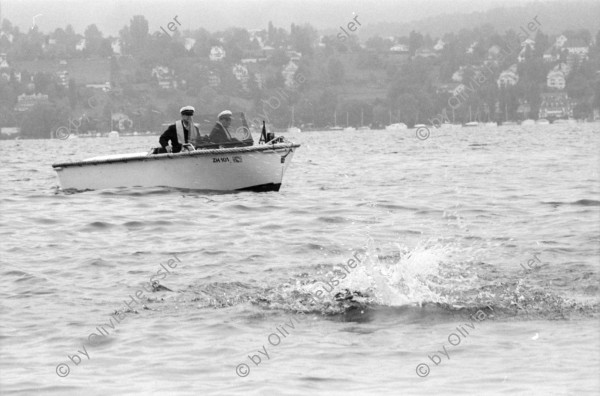 Image of sheet 19940340 photo 29: Polizeiaspirantinnen Polizei und Verkehrspolizisten beamte und Beamtinnen in Badehosen vor der Seeüberquerung Zürichsee Badi Wollishofen. 1600m nach Tiefenbrunnen. Nr. 0 -3 Herr Zurfluh Chef der Ausbildung. Ziel. Nr. 25 Fredi Bachmann Gewinner 32 Minuten. Schwimmer im See Motorboote Polizei. Frau streicht Schwimmer auf Liste mit Fotos. Zürich 1994